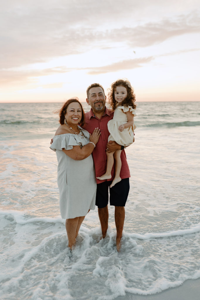 Grandparents with their grand daughter on the beach by Michelle Medina Photography.
